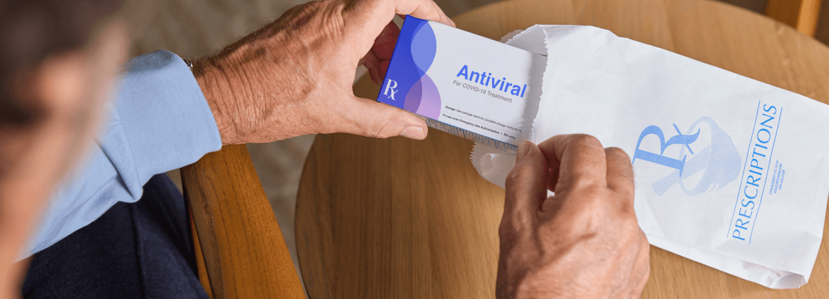 hands pulling out antiviral medication from a prescription bag