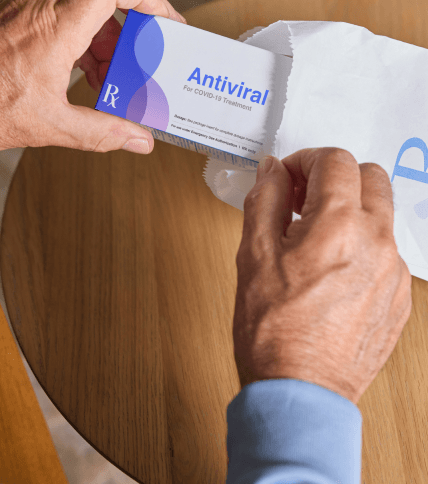 hands pulling out antiviral medication from a prescription bag